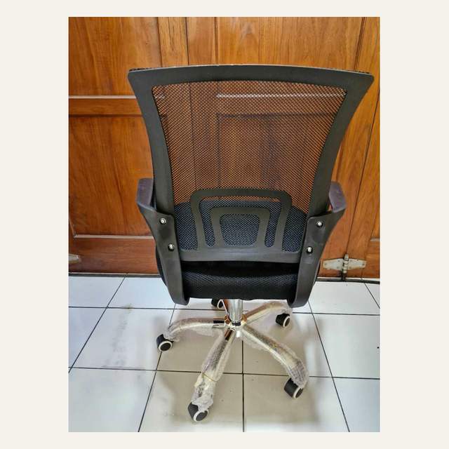 Sisi belakang kursi beroda hitam memperlihatkan rangka sandaran dan baut sambungan armrest.