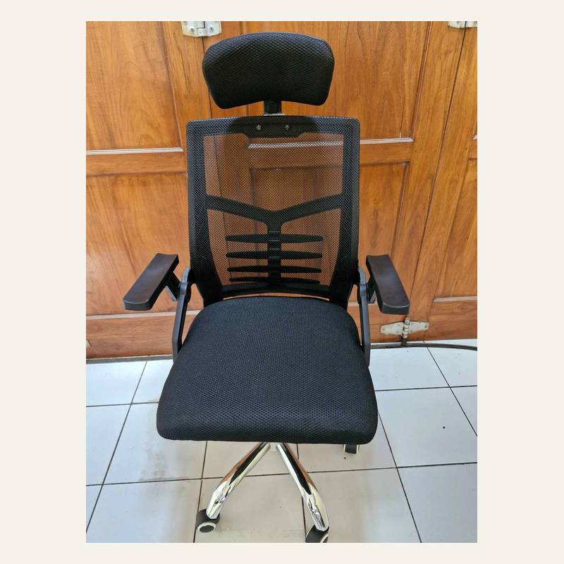 Kursi beroda hitam bersandaran kepala tampak depan dengan rangka punggung bercabang dan armrest datar.