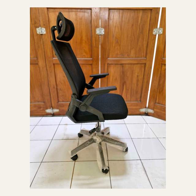 Kursi kantor hitam tampak samping dengan sandaran jaring, headrest, armrest, dan kaki lima cabang beroda.