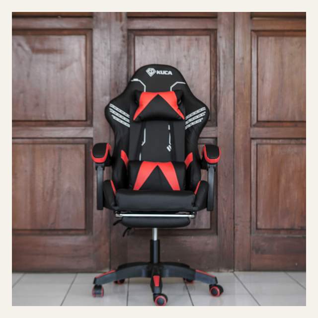 Kursi gaming hitam merah tampak depan bertulisan KUCA dengan dua bantal dan sandaran kaki terbuka.