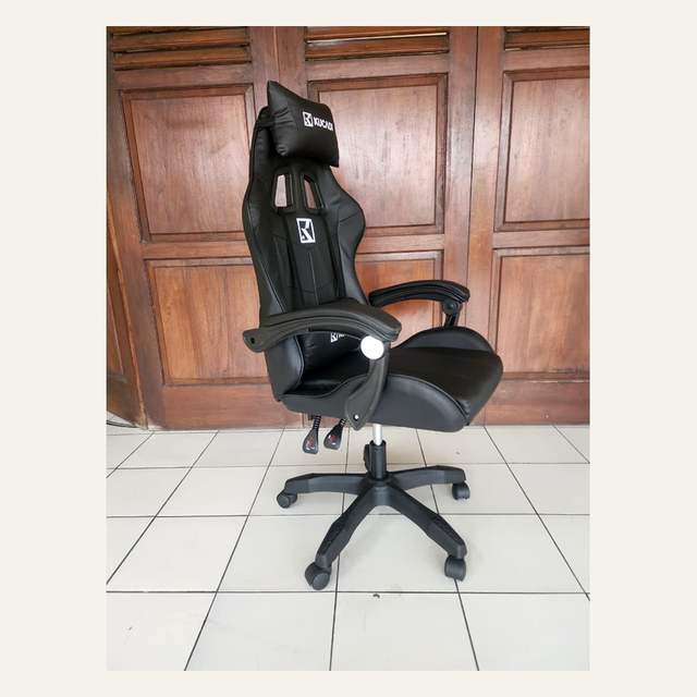 Kursi gaming hitam tampak serong memperlihatkan dua tuas kecil di bawah dudukan dan kaki beroda.