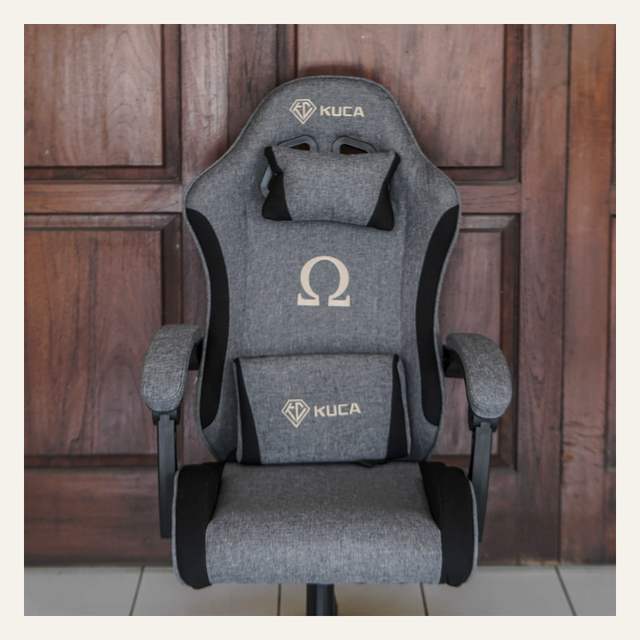 Kursi gaming abu-abu tampak depan bertulisan KUCA dan simbol omega, bagian kaki di luar bingkai.