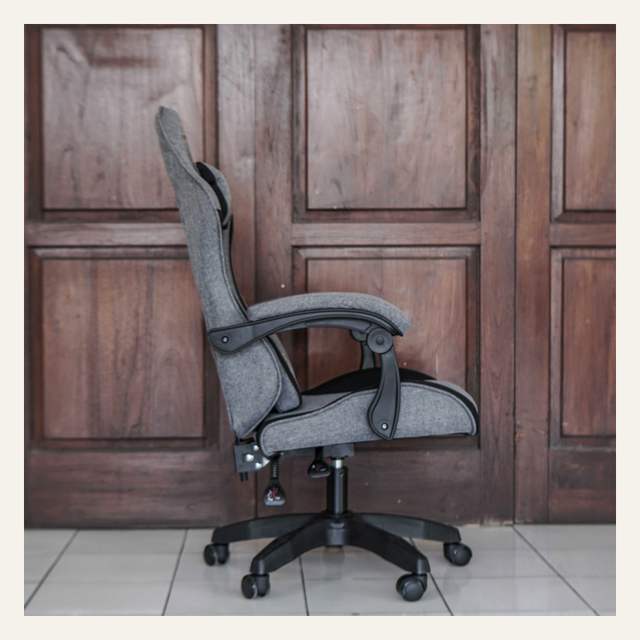 Kursi gaming abu-abu tampak samping dengan armrest melengkung, dua tuas, dan kaki lima cabang beroda.