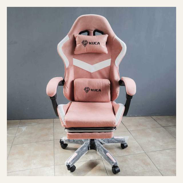 Kursi gaming merah muda tampak depan dengan dua bantal bertuliskan KUCA dan sandaran kaki terbuka.