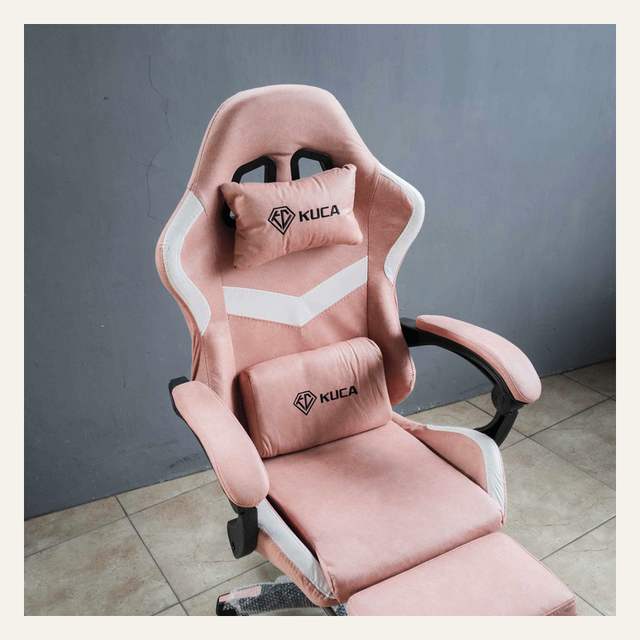 Kursi gaming merah muda dilihat dari serong atas dengan dua bantal KUCA dan sandaran kaki terbuka.