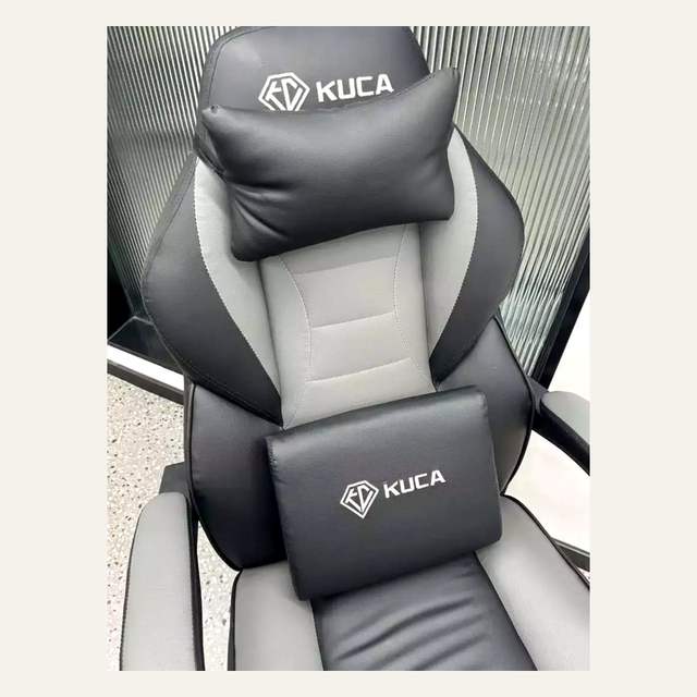 Detail bagian atas kursi hitam abu-abu berlogo KUCA dengan bantal leher dan bantal kecil.