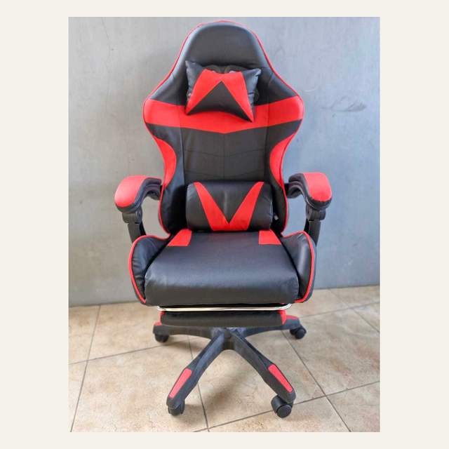 Kursi hitam merah difoto dari depan agak dekat dengan bantal leher dan bantal pinggang terpasang.