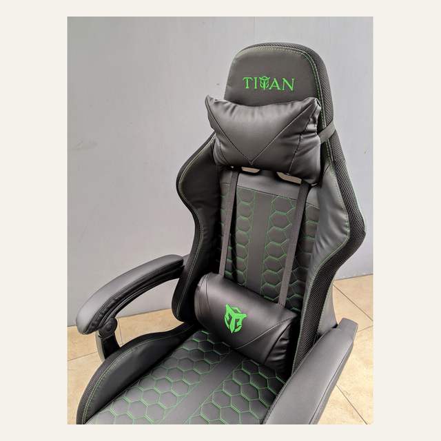 Foto dekat sandaran kursi TITAN hitam dengan jahitan hijau segi enam dan dua bantal.