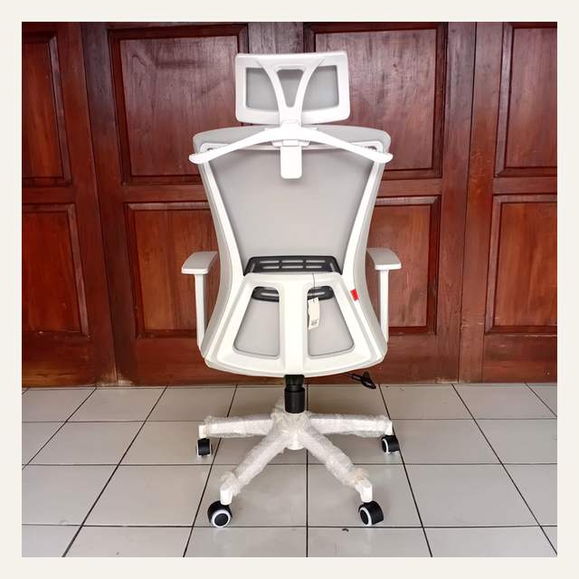 Kursi kerja putih dilihat dari belakang di depan pintu kayu cokelat, kaki terbungkus plastik gelembung.