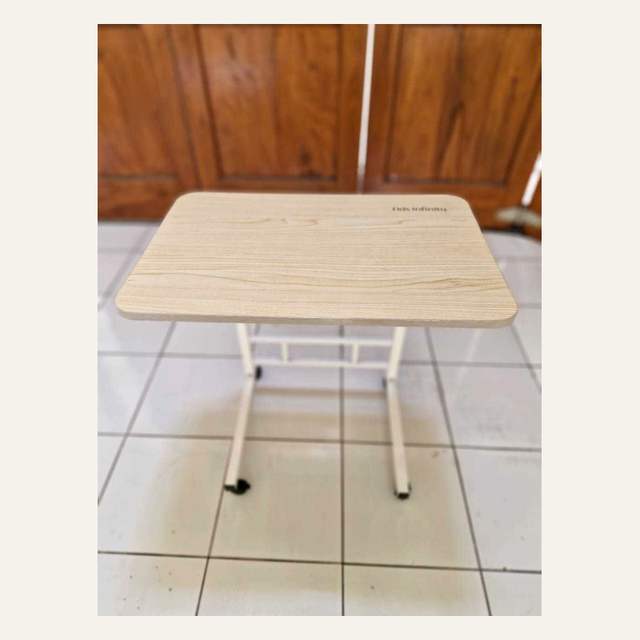 Meja kecil bermotif serat kayu terang dengan rangka pipa putih menyilang dan roda kecil hitam.