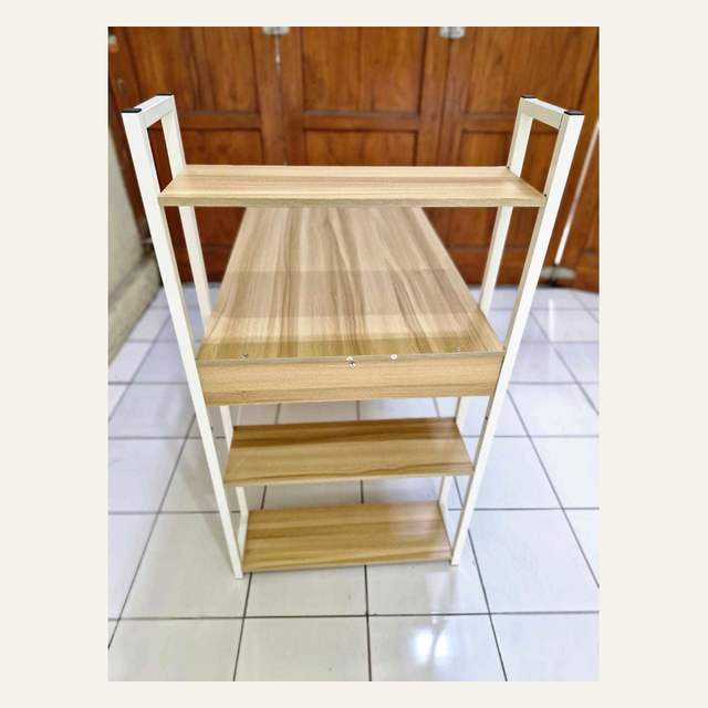 Foto dekat bagian rak susun bermotif serat kayu dengan rangka putih, sebagian meja terpotong di luar bingkai.