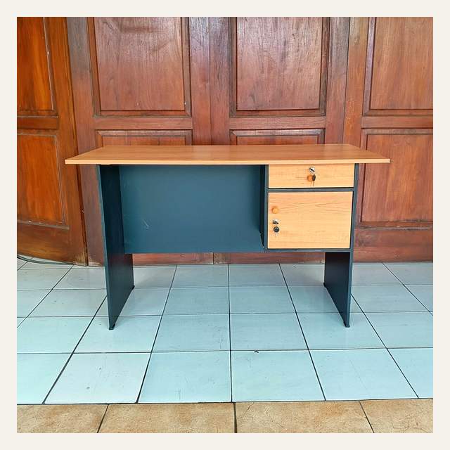 Meja kerja bermotif serat kayu tampak depan dengan panel hitam dan dua laci berkunci di kanan.