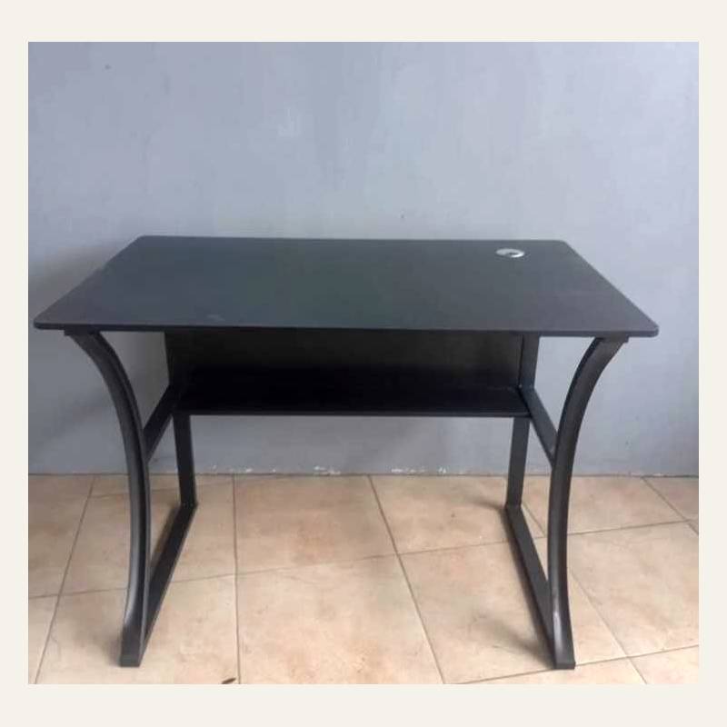 Meja hitam tampak depan dengan rak bawah dan kaki melengkung, foto agak buram beresolusi rendah.