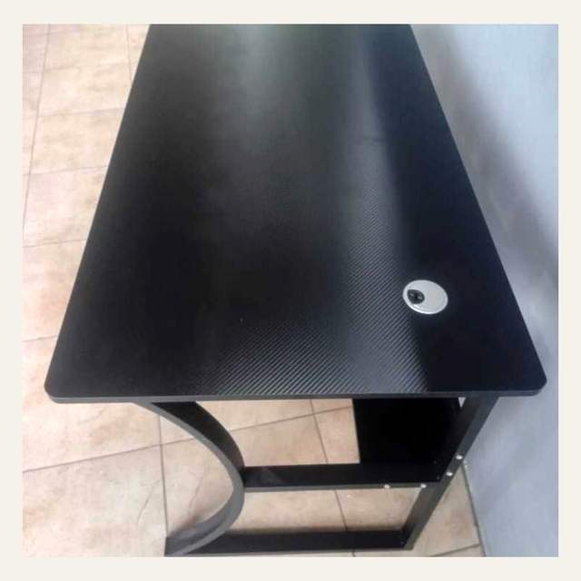 Foto dekat permukaan meja hitam bermotif diagonal dengan satu lubang bercincin perak.
