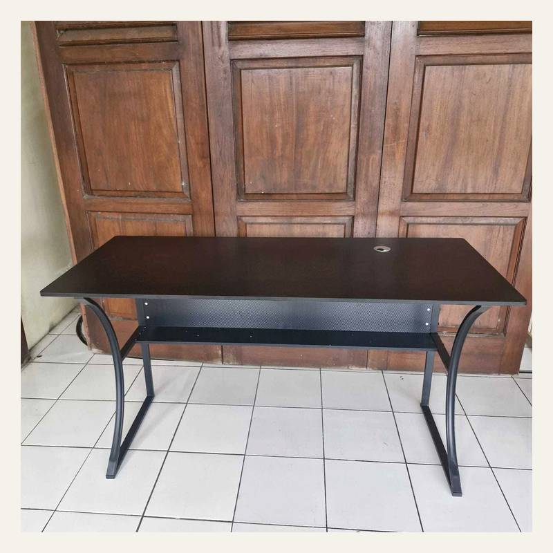 Meja cokelat tua dengan panel bermotif jaring dan kaki hitam melengkung di depan pintu kayu.