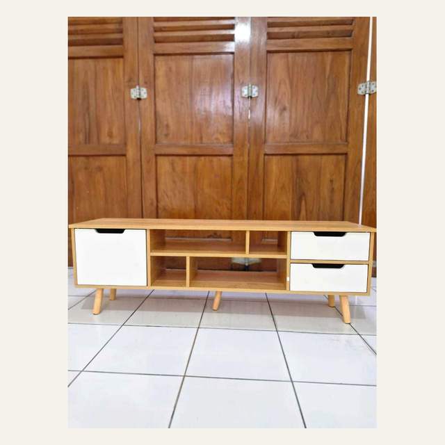 Rak rendah motif kayu terang dengan satu pintu dan dua laci putih di lantai keramik putih.