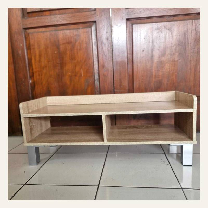 Rak rendah motif kayu terang dengan dua ruang terbuka dan empat kaki perak di lantai keramik.